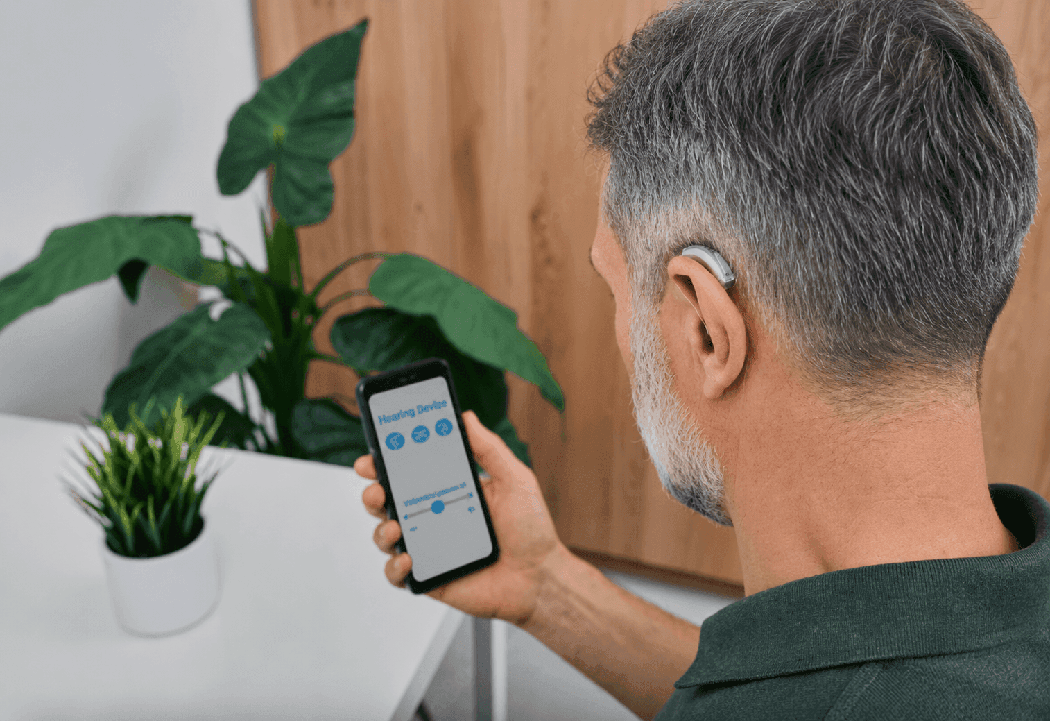 Man adjusting hearing aid settings with a smartphone app