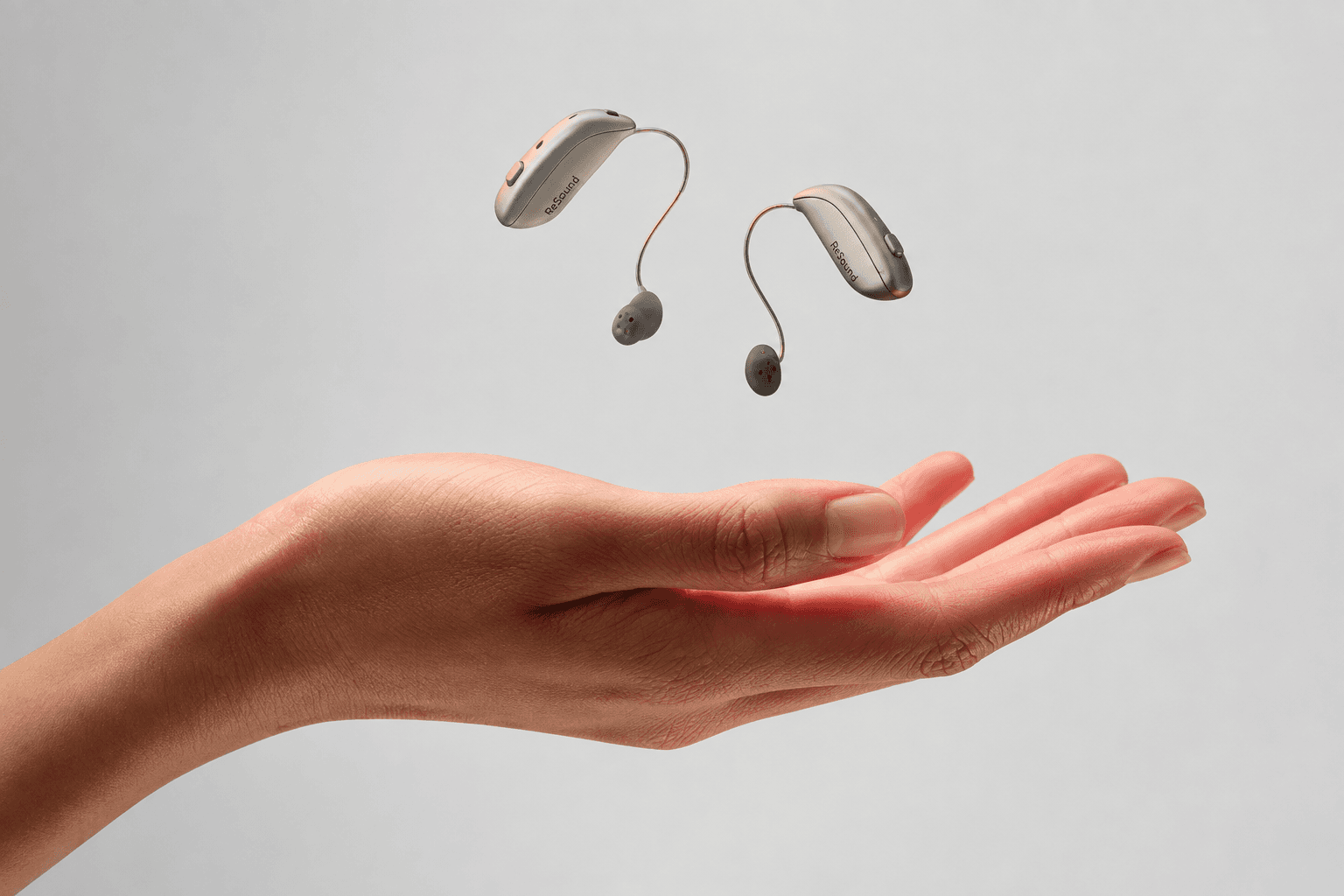 ReSound Sensia hearing aids shown above an open hand.