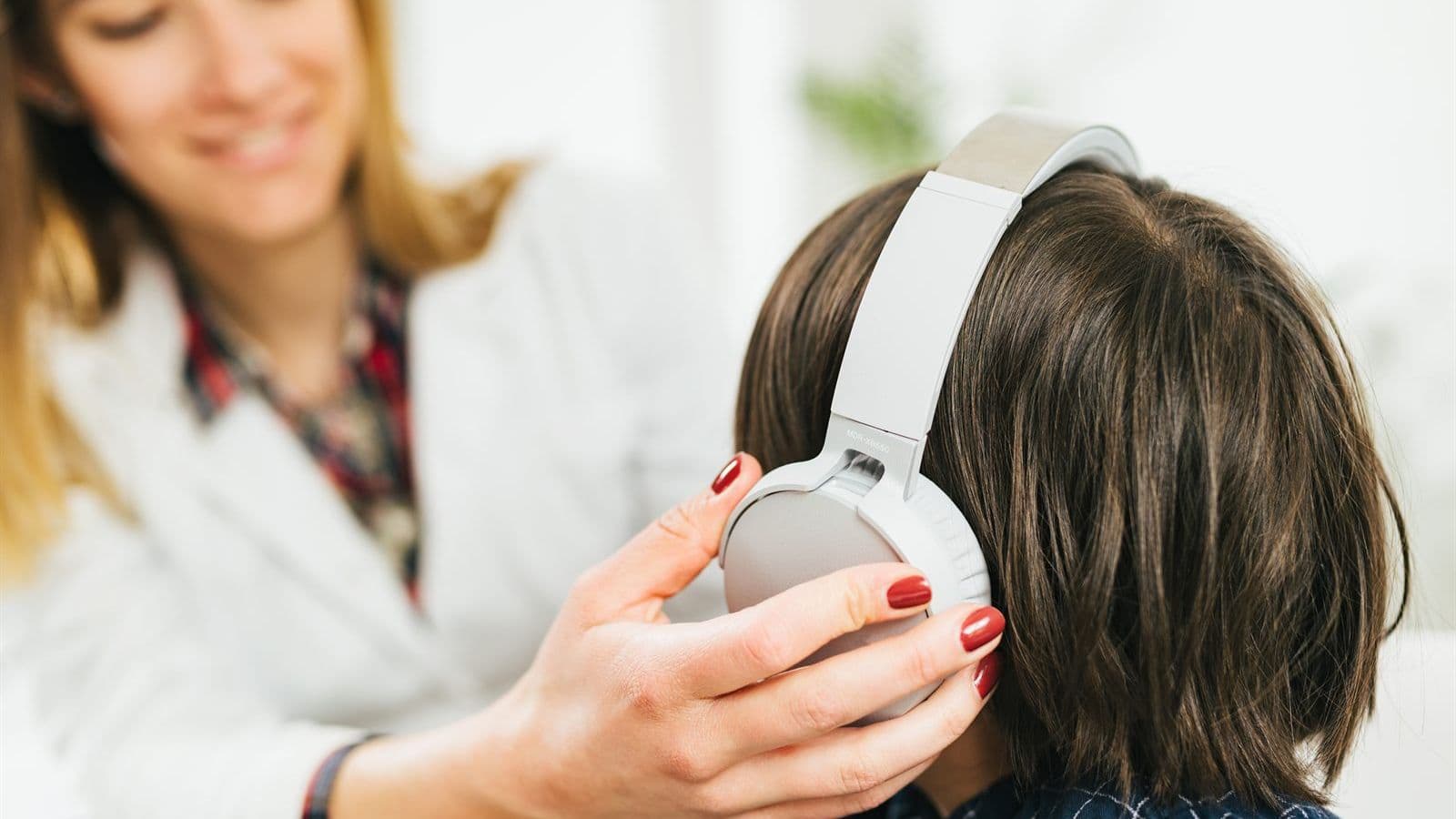 An audiologist placing headphones on a child during a hearing test