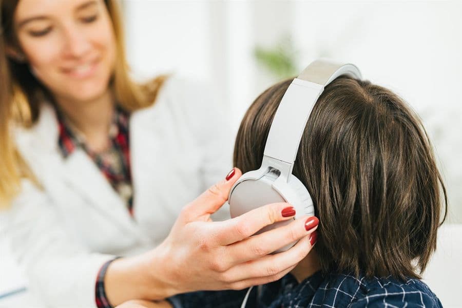 An audiologist placing headphones on a child during a hearing test