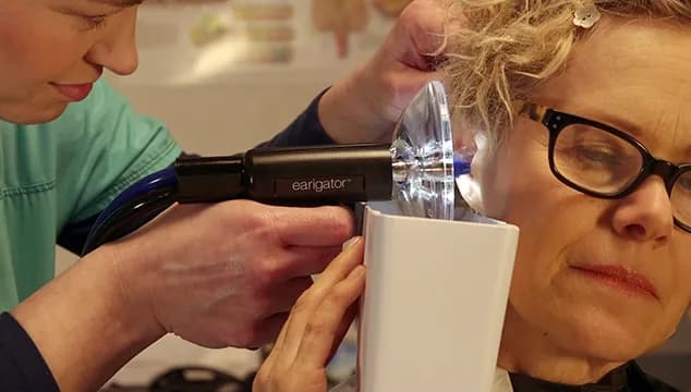 Earigator device being used during a cerumen removal procedure